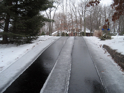 Asphalt driveway with heated tire tracks.