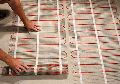 Floor heating mats being installed in basement floor.