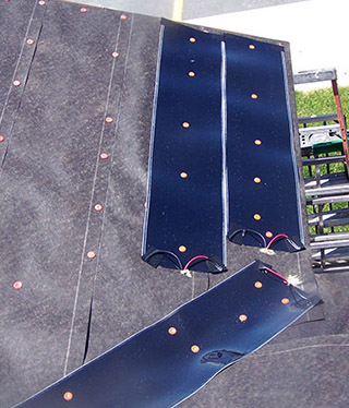 Low-voltage roof heating system installed being installed along the roof edge of a commercial structure